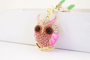 Close-up of golden owl keychain with pink rhinestones and enamel wings detail