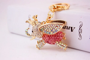 Macro shot of gold-plated flying elephant keychain with pink and white rhinestones