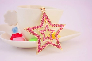 Detailed macro view of a gold-plated double star pendant with inlaid pink crystals