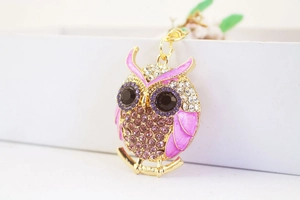 Macro view of gold alloy owl keychain with pink enamel and sparkling rhinestones