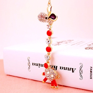 Golden giraffe keychain with red enamel and sparkling crystals on a book