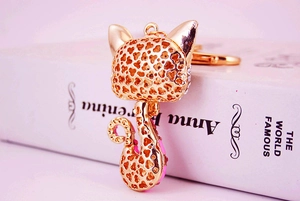 Détail d'un porte-clés chat doré avec strass roses et motif de cœur découpé