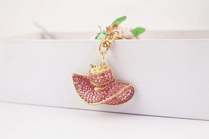 Close-up of golden keychain featuring a wide-brim hat charm with pink rhinestones