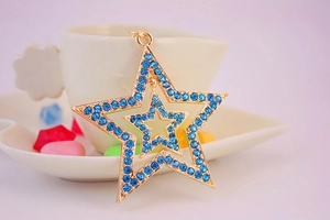 Close-up of golden hollow star keychain with blue rhinestones on a decorative background