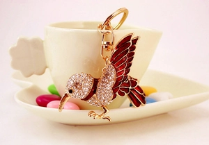 Detailed close-up of a crystal kingfisher keychain hanging on a white ceramic cup