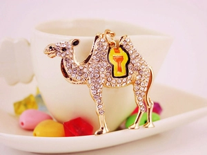 Detailed close-up of golden camel keychain with sparkling rhinestones and colorful saddle