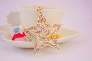Detail of gold hollow double star keychain with rhinestones against a ceramic cup