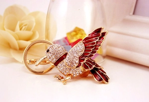 Macro detail of kingfisher keychain with red enamel wings and crystal rhinestones