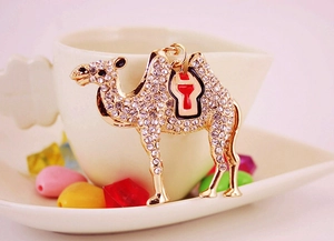 Detailed view of camel keychain with rhinestones and enamel saddle on a white cup