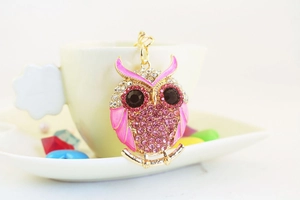 Close-up of pink owl keychain with sparkling rhinestones hanging on a coffee cup