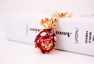 Close-up of a red enamel lucky money bag keychain with rhinestones and gold accents