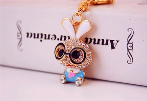 Macro shot of cute cartoon rabbit keychain with sparkling rhinestones and blue enamel dress
