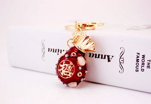 Detail of red enamel fortune bag keychain with gold plating and sparkling rhinestones