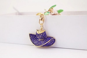 Detail of blue rhinestone hat keychain with gold alloy base on a white gift box