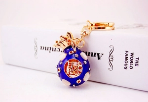 Detail view of lucky money bag keychain with blue enamel, crystals, and gold lobster clasp