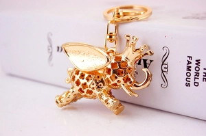 Detailed close-up of golden flying elephant keychain with crown and rhinestone accents