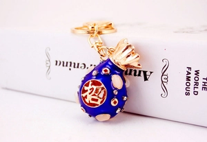 Detailed view of dark blue enamel lucky money bag keychain with crystal diamond accents