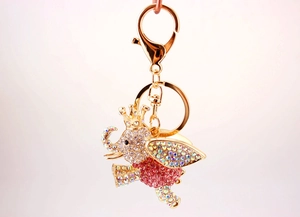 Detailed macro view of crystal-encrusted flying elephant keychain with a golden crown