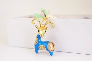 Close-up of golden goat keychain with blue enamel and sparkling rhinestone details