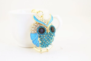 Detailed macro shot of creative crystal owl keychain with blue rhinestones and gold ring