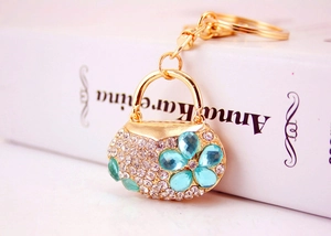 Detail of golden purse keychain with sky blue rhinestone flower pattern on book