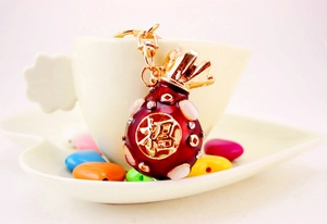 Close-up of red enamel lucky bag keychain with pink gems and gold lobster clasp