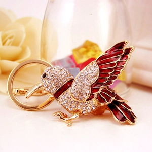 Charming bird keychain featuring sparkling crystals and red enamel in a golden finish