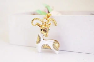 Detailed close-up of a goat pendant featuring white enamel and sparkling rhinestones