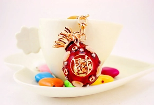 Detailed view of a red money bag keychain with crystal diamonds and golden bow ornament