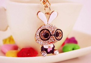 Detailed macro view of gold-tone bunny keychain with rhinestones and black glasses