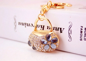 Macro detail of gold purse-shaped keychain with blue rhinestone floral pattern