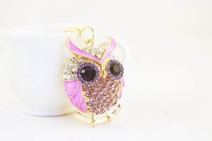 Close-up of pink owl keychain with sparkling purple rhinestones and gold-tone finish