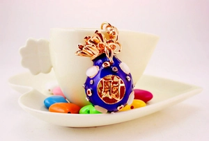 Detailed view of a blue enamel fortune bag keychain with crystals and gold lettering