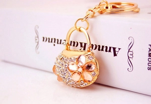 Close-up of golden handbag keychain with floral crystals on a white book surface