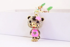 Gros plan du porte-clés tigre doré serti de strass avec robe en émail rose et fleurs