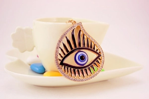 Detailed close-up of water drop evil eye pendant with blue enamel and white rhinestones