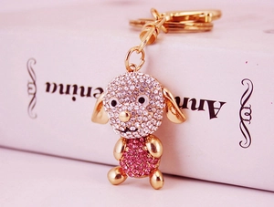 Détail d'un porte-clés chien scintillant serti de strass roses et blancs sur métal doré