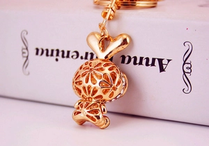 Detail of a hollow gold bunny keychain with white rhinestones on a decorative book