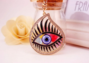 Close-up of golden Evil Eye keychain with blue rhinestones and black eyelash details