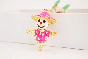 Close-up of pink enamel scarecrow pendant with sparkling crystals and gold metal finish