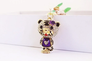 Détail d'un porte-clés tigre créatif avec cristaux blancs et émail violet élégant