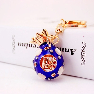 Blue money bag keychain with gold lettering and crystal beads on a white book background