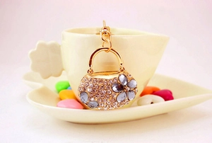 Detail of luxury rhinestone handbag keychain with grey flower pattern and gold finish
