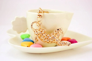 Close-up of golden leopard keychain with white rhinestones on a ceramic cup rim