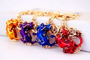 Détail de quatre porte-clés Pixiu en émail coloré avec strass et placage métallique doré