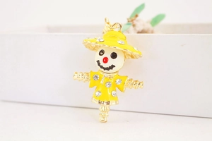 Close-up of golden scarecrow charm with yellow enamel finish and sparkling rhinestones