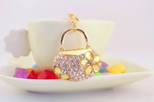Close-up of golden handbag keychain with sparkling white rhinestones and yellow crystal flowers