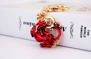 Détail du porte-clés PiXiu rouge et doré orné de cristaux et de strass brillants
