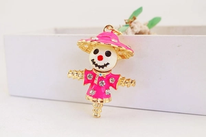 Detailed close-up of a cute rhinestone-studded scarecrow pendant with pink enamel coating