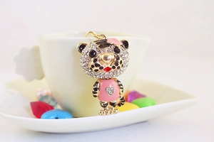 Détail d'un porte-clés tigre mignon avec robe en émail rose et cristaux brillants